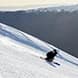 A skier carves down a ski slope at sunset.