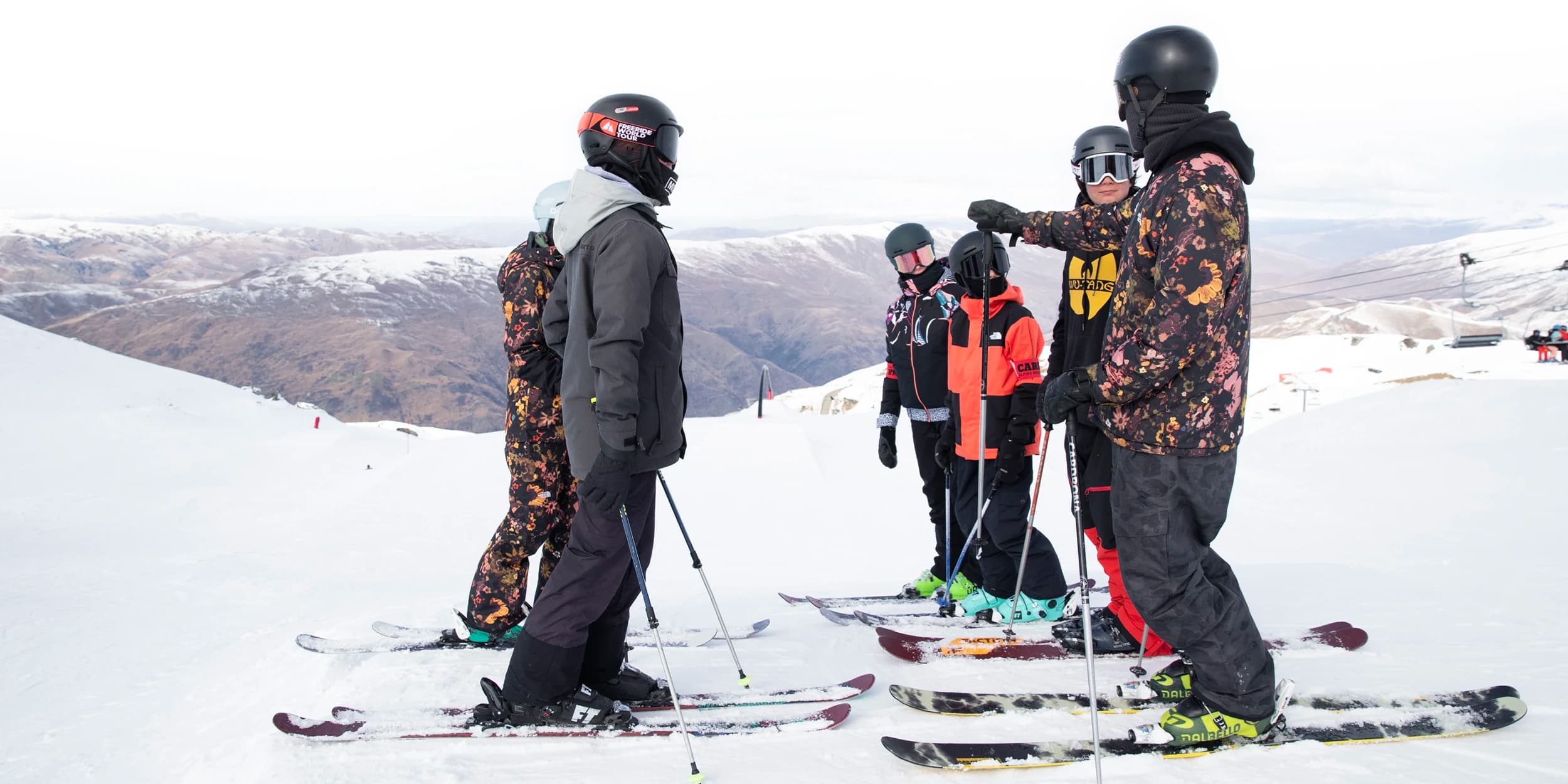 A group of skiers at Cardrona Alpine Resort listens attentively as an instructor points out the terrain, preparing them for an exciting day on the slopes.