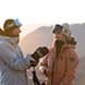 Two skiers put their gear on, ready for a big day of riding.