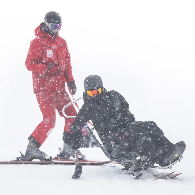 An adaptive skier uses their out rigger to turn whilst on a lesson at Cardrona.