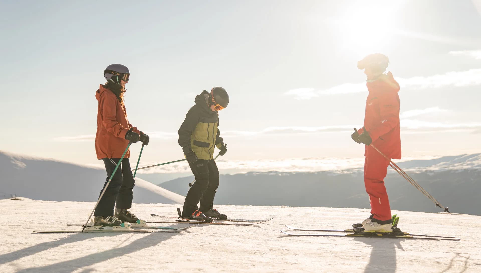 Two people taking a ski lesson at the top Treble Cone Ski Field, New Zealand, with instructors guiding them on snow-covered slopes and a panoramic view of surrounding mountains.