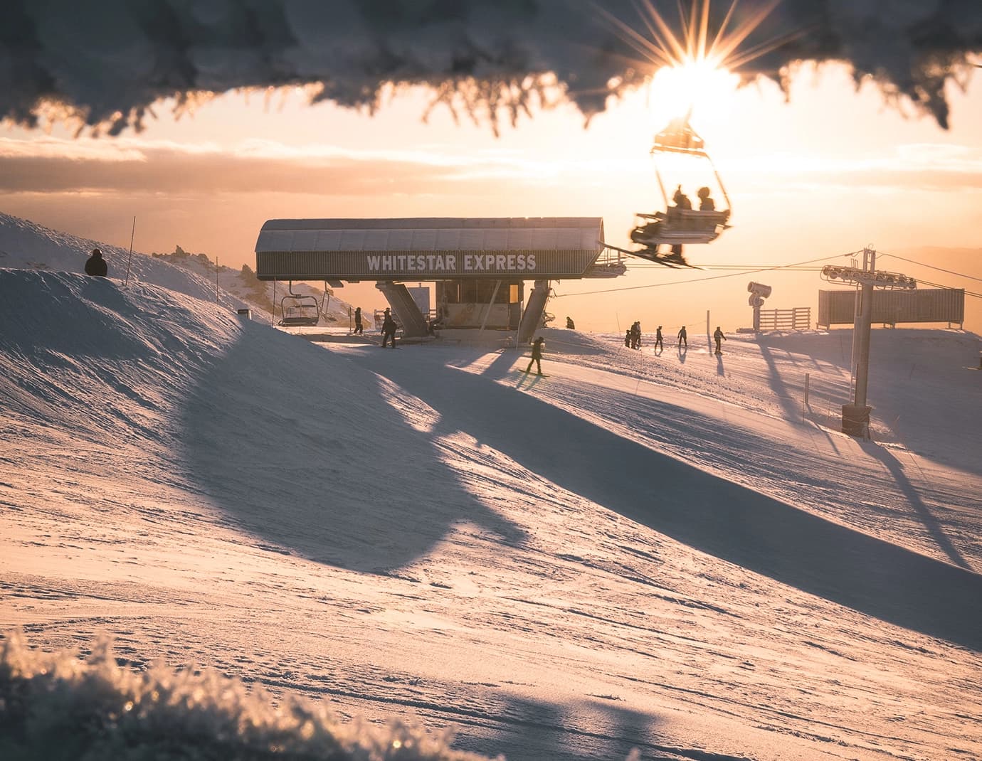 The sun rises over a ski resort, with a chair lift called "Whitestar Express" in the foreground. 