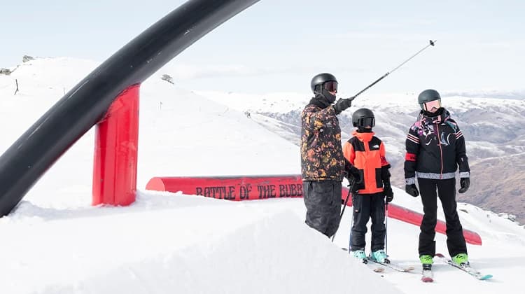 An instructor at Cardrona Alpine Resort points out features in the terrain park to young skiers, helping them prepare for a ski event.