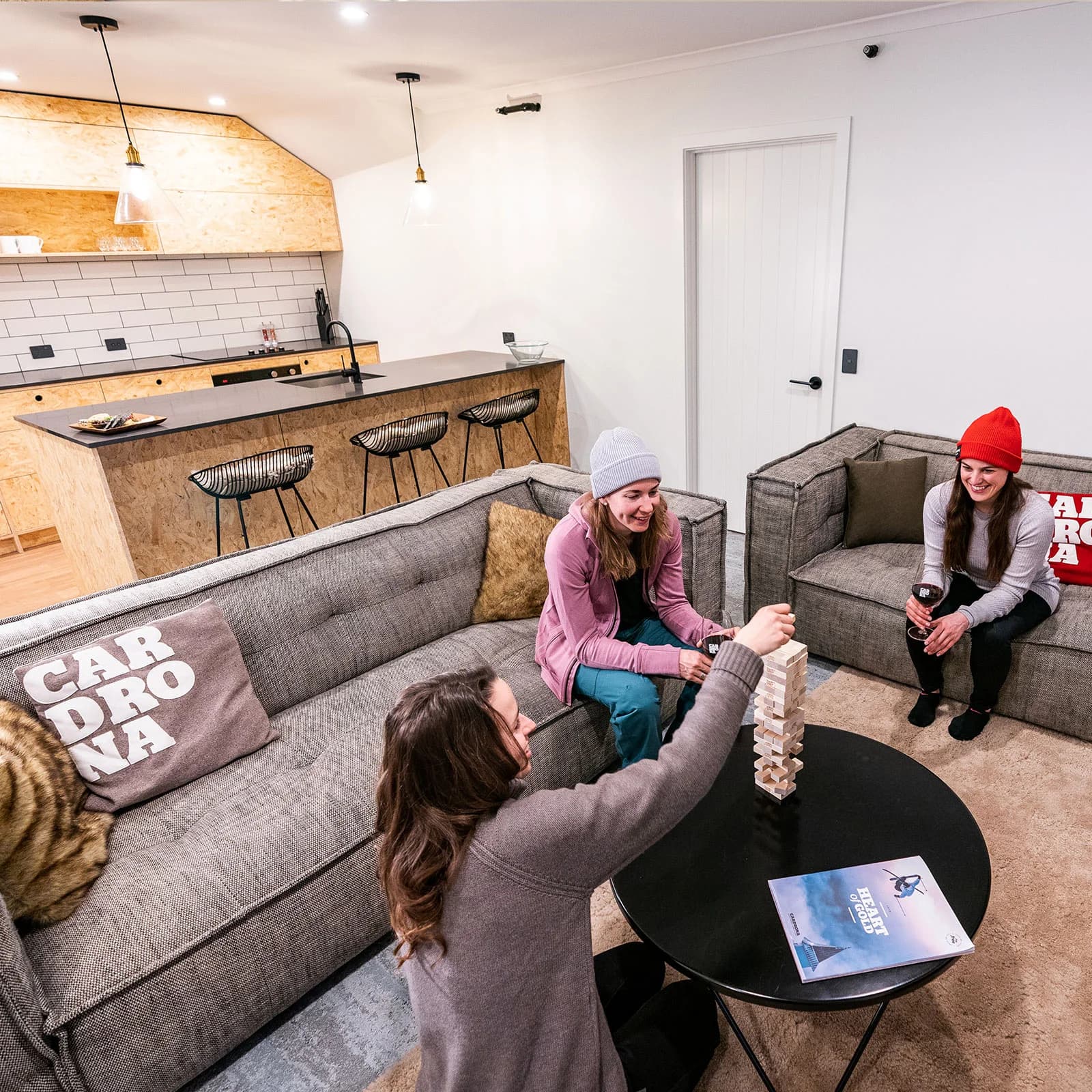 Three women enjoy a game of Jenga in a cosy studio apartment. 