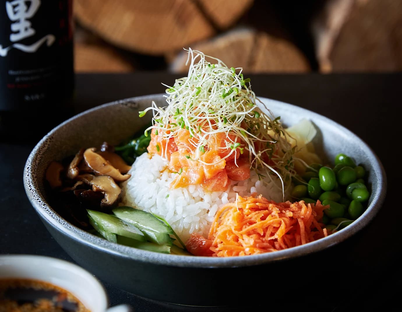 Bento bowl of rice, salmon, carrot, cucumber and beans, topped with bean sprouts.