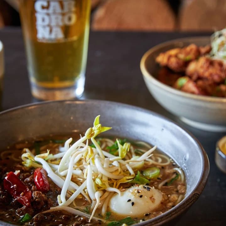 A bowl of freshly made noodles with an entree and two drinks.
