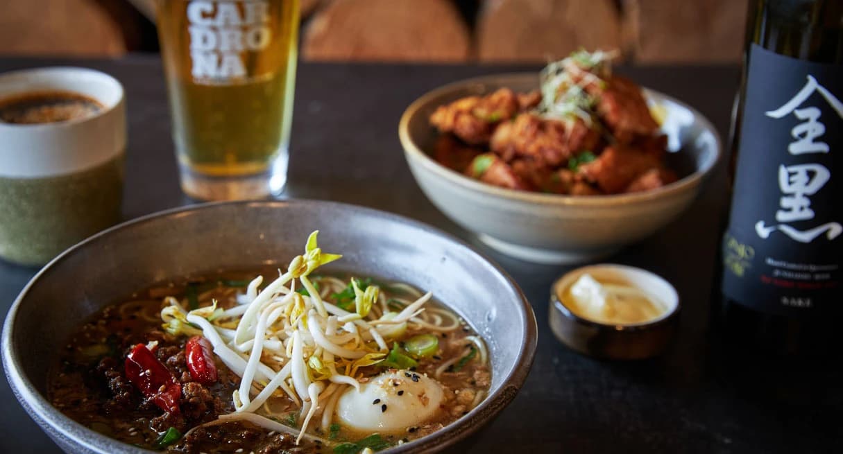 A bowl of freshly made noodles with an entree and two drinks.
