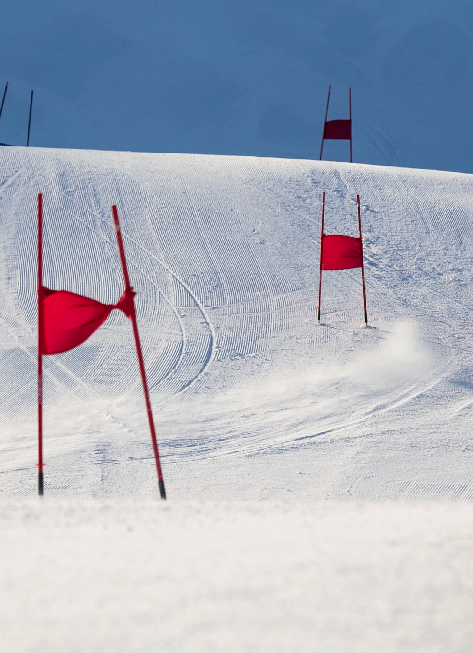 Empty race gates line a freshly groomed slope under clear skies.