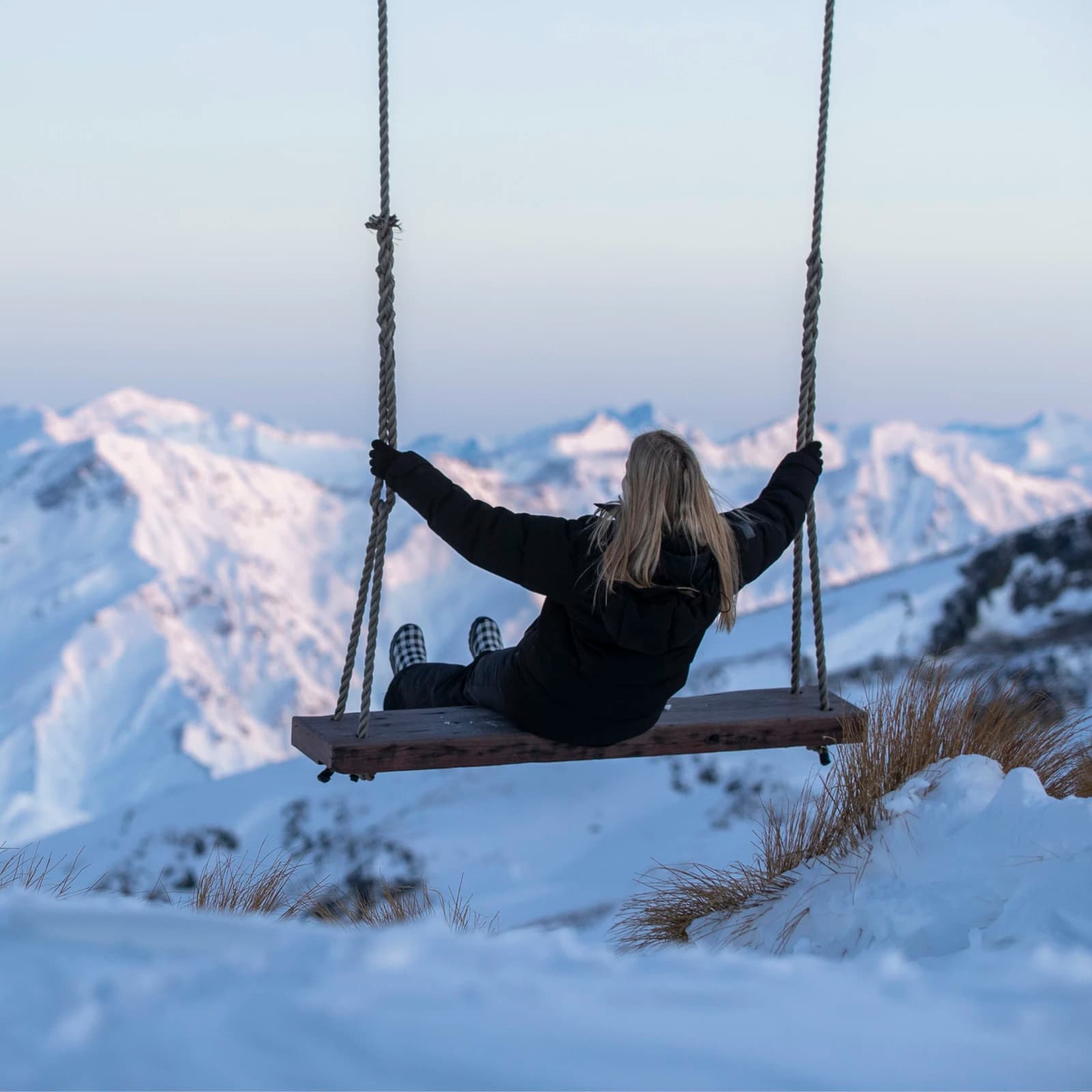 A lady rides a swing at the top of the Cardrona ski field.