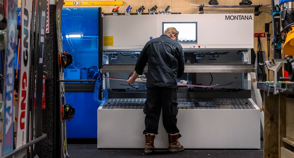 A person uses an edging machine to wax and edge some skis.
