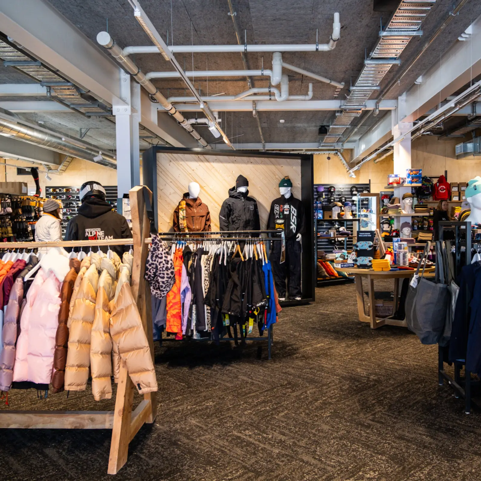 Interior of the Cardrona retail store featuring racks of colourful winter jackets, mannequins in snow gear, and shelves stocked with outdoor accessories and merchandise.