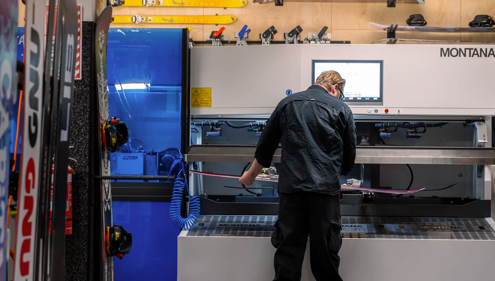 A person uses an edging machine to wax and edge some skis.
