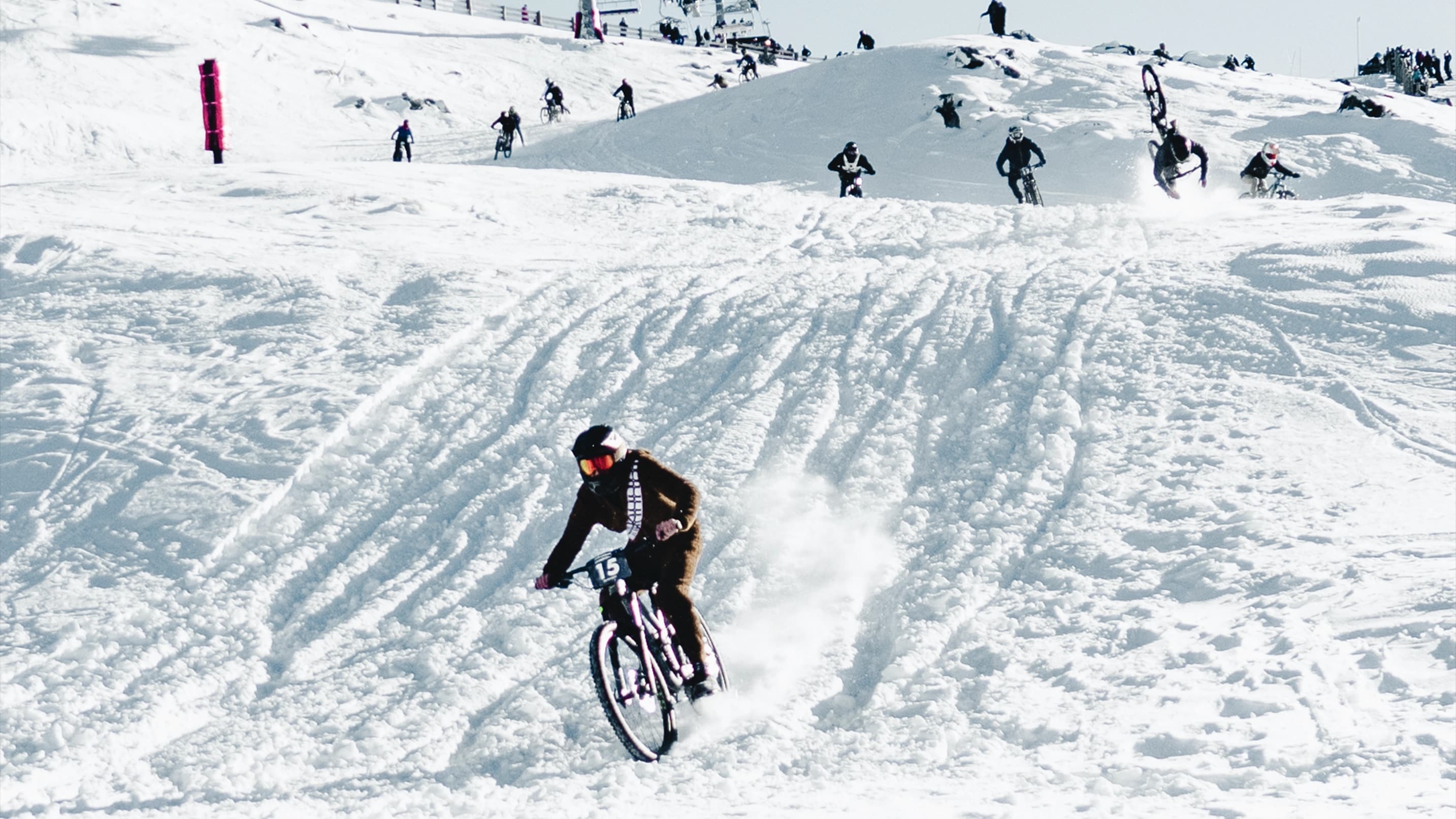 Ski field event where people mountain bike down snowy tracks.