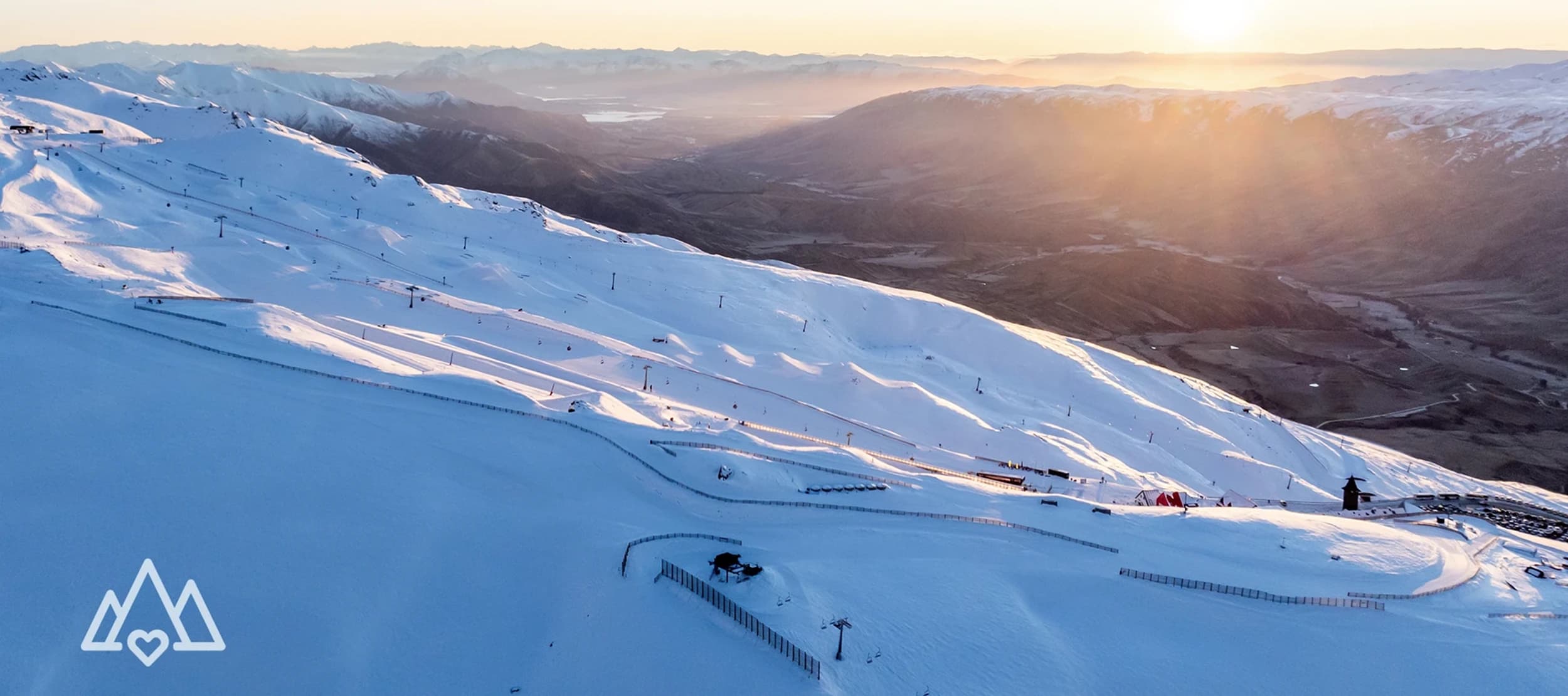 An aerial view of Cardrona Alpine Resort at sunrise. Showcases base and park from above.