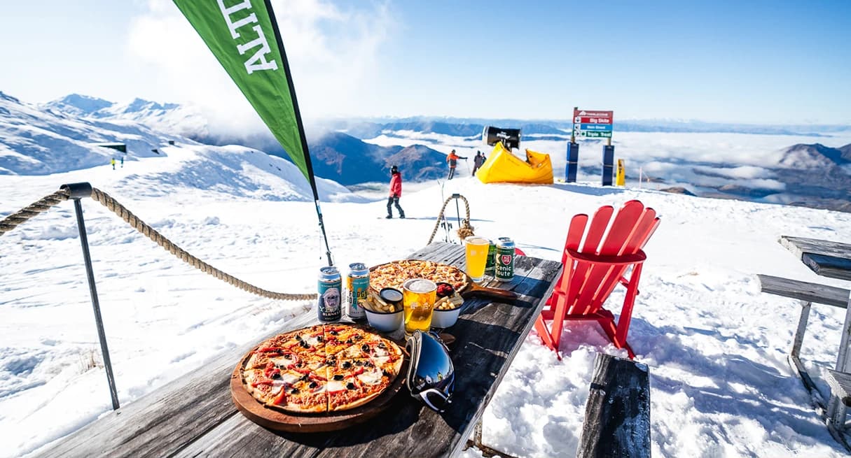 A picnic table with beers and pizza at the Altitude bar, Treble Cone.