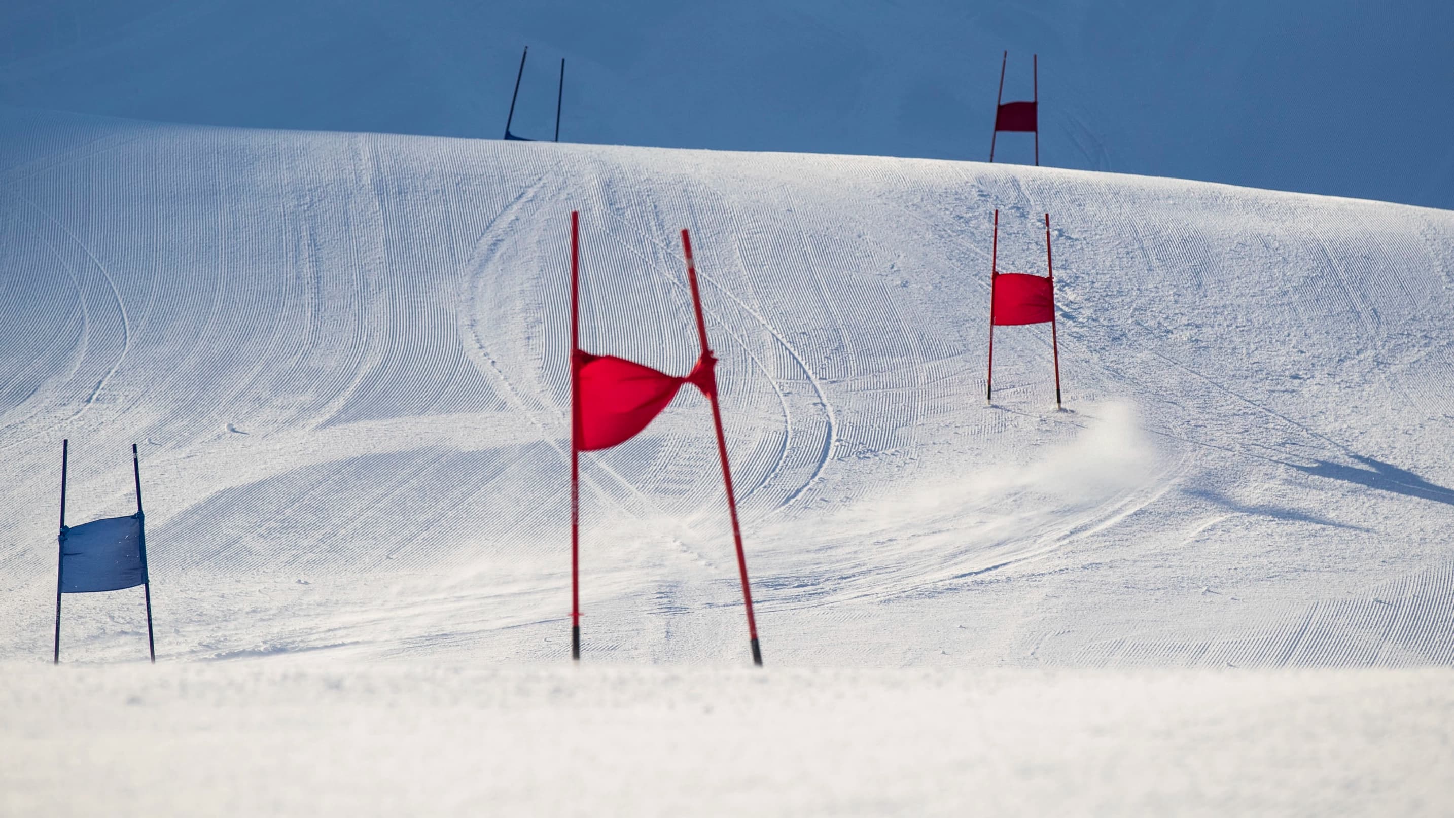 Empty race gates line a freshly groomed slope under clear skies.