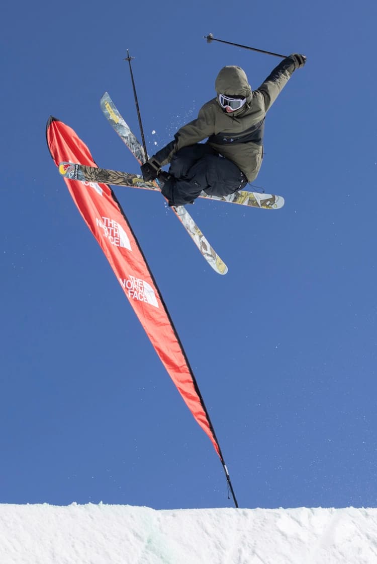 Skier in a black and green jacket at Cardrona Alpine resort doing an aerial trick