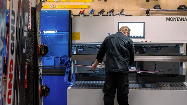 A person uses an edging machine to wax and edge some skis.
